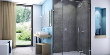 Dans une salle de bains bleue et grise, la douche est équipée d'un paroi Escura de Sanswiss