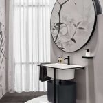 Meuble de salle de bains surmonté d'un gros miroir rond.