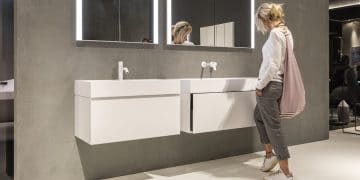 Une femme regardant un meuble de salle de bains blanc au salon de milan