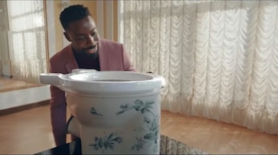 un homme penché sur une cuvette WC ancienne décorée