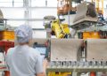 Femme de dos devant une ligne de production de WC, usine VitrA en Turquie