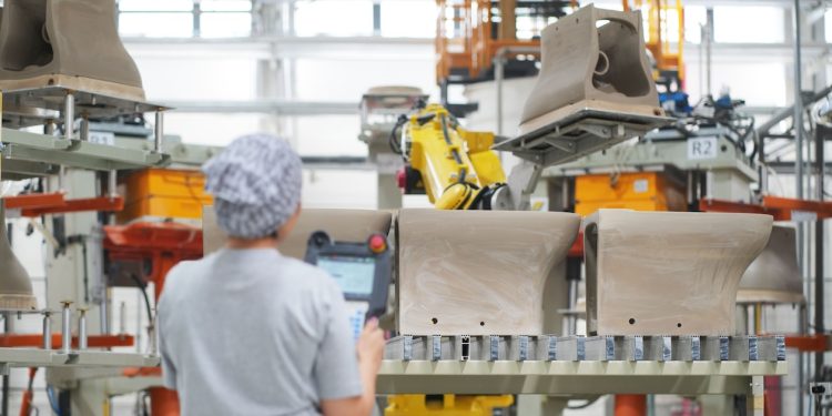 Femme de dos devant une ligne de production de WC, usine VitrA en Turquie