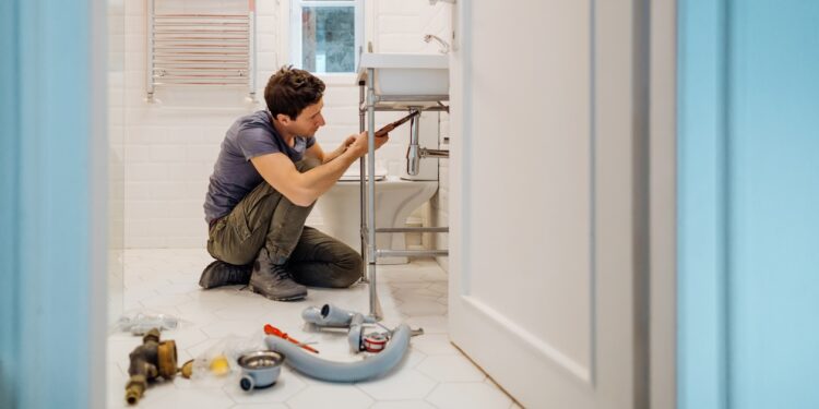 Jeune homme installant une bonde de lavabo