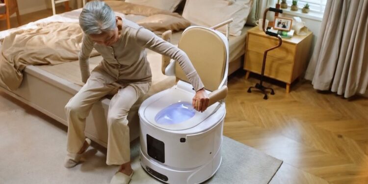 Une personne âgée s'installant sur le robot WC positionné près de son lit.